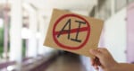 A hand holds a cardboard sign with the letters 