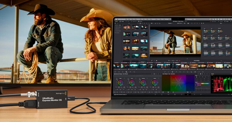 A laptop shows video editing software with a Western scene. Two people in cowboy hats lean on a fence in the background. A compact UltraStudio device is connected to the laptop with a cable.