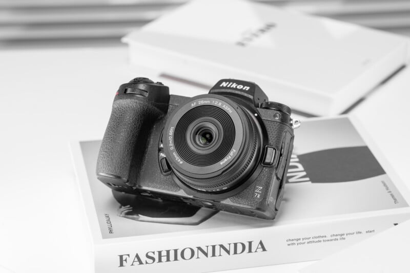 A Nikon Z7 II camera with an attached lens rests on a book titled "FASHIONINDIA" in a bright, minimal setting.