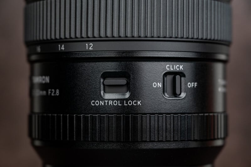 Close-up of a camera lens showing a "CONTROL LOCK" switch, a "CLICK" slider with ON and OFF positions, and visible focus ring markings for 12 and 14 mm.