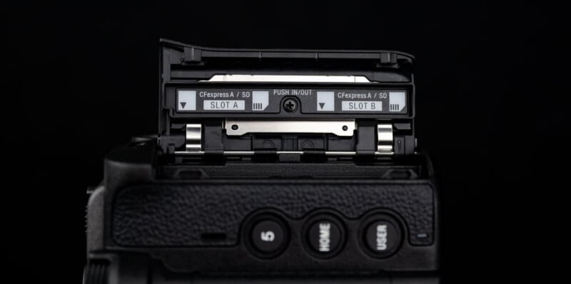Close-up of a camera's dual memory card slots labeled "CFexpress A / SD" with slots A and B visible, and textured camera body buttons below the open compartment.