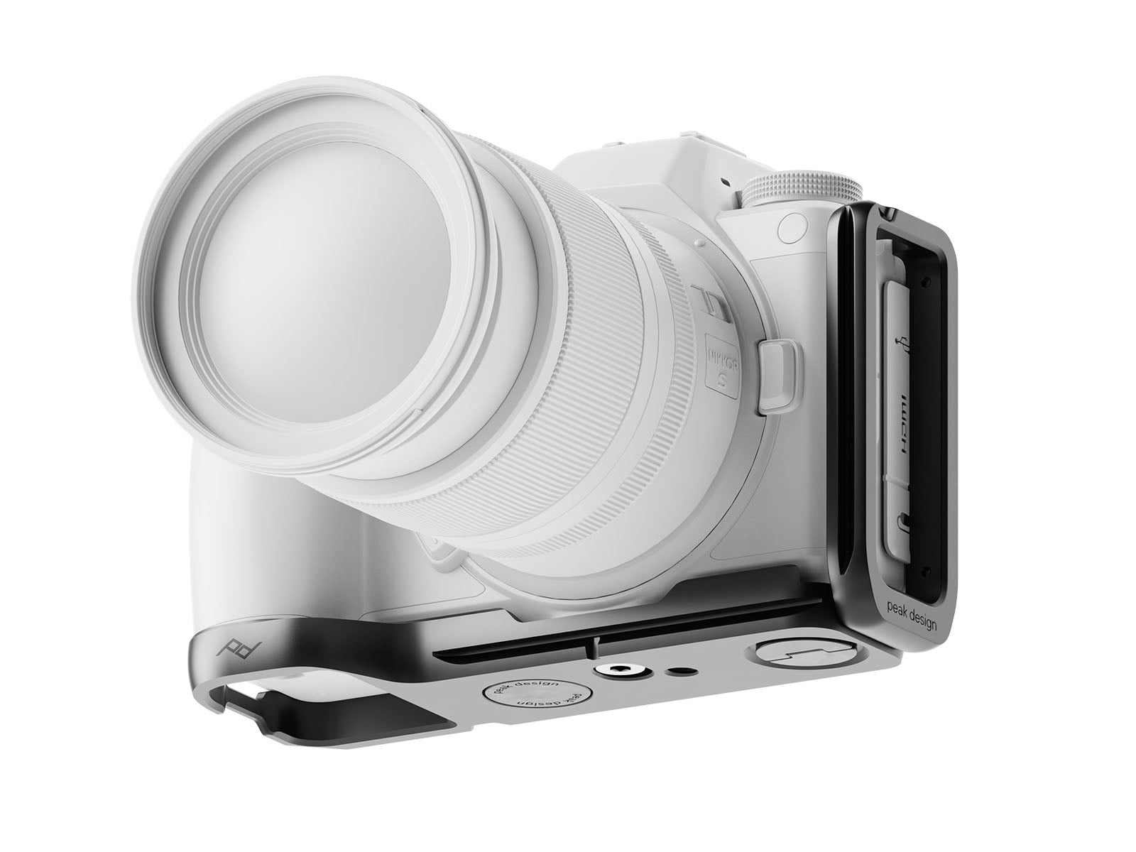 A digital camera with a large lens is attached to a metal L-bracket mount, shown at an angle. The bracket is engraved with "Peak Design" and includes screws and slots for tripod mounting.