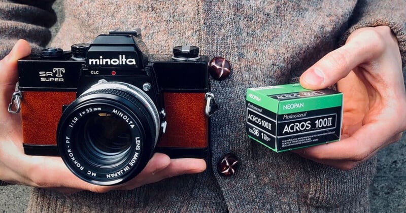 Person holding a vintage Minolta SR-T Super camera in one hand and a box of Fujifilm Neopan Acros 100 II black-and-white film in the other.