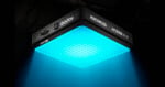 A square Godox KNOWLED AM1800R LED light panel emits a bright blue glow downward, illuminating the area below in a dark environment.