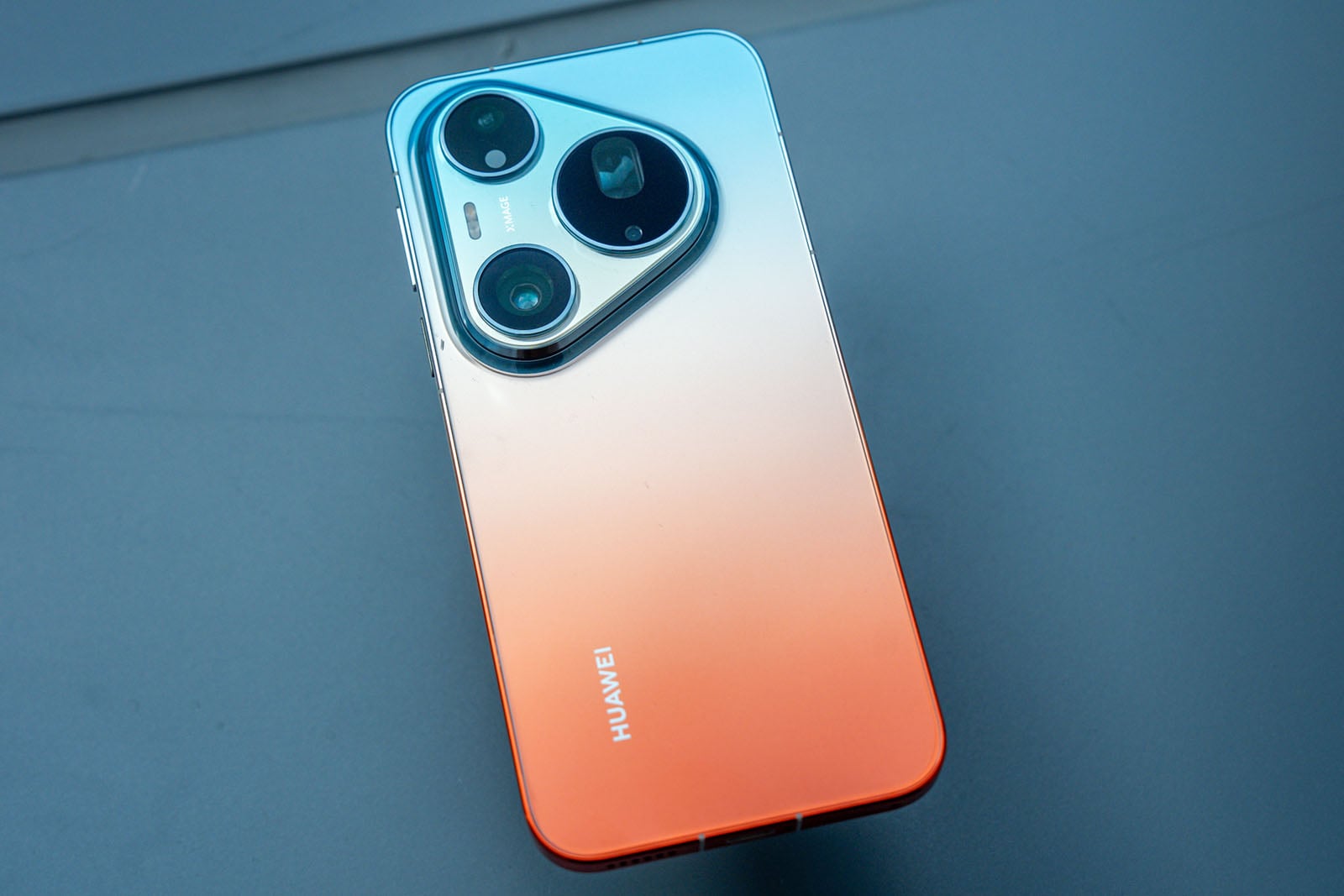 A Huawei smartphone with a gradient blue to orange back cover and three rear cameras arranged in a triangle.