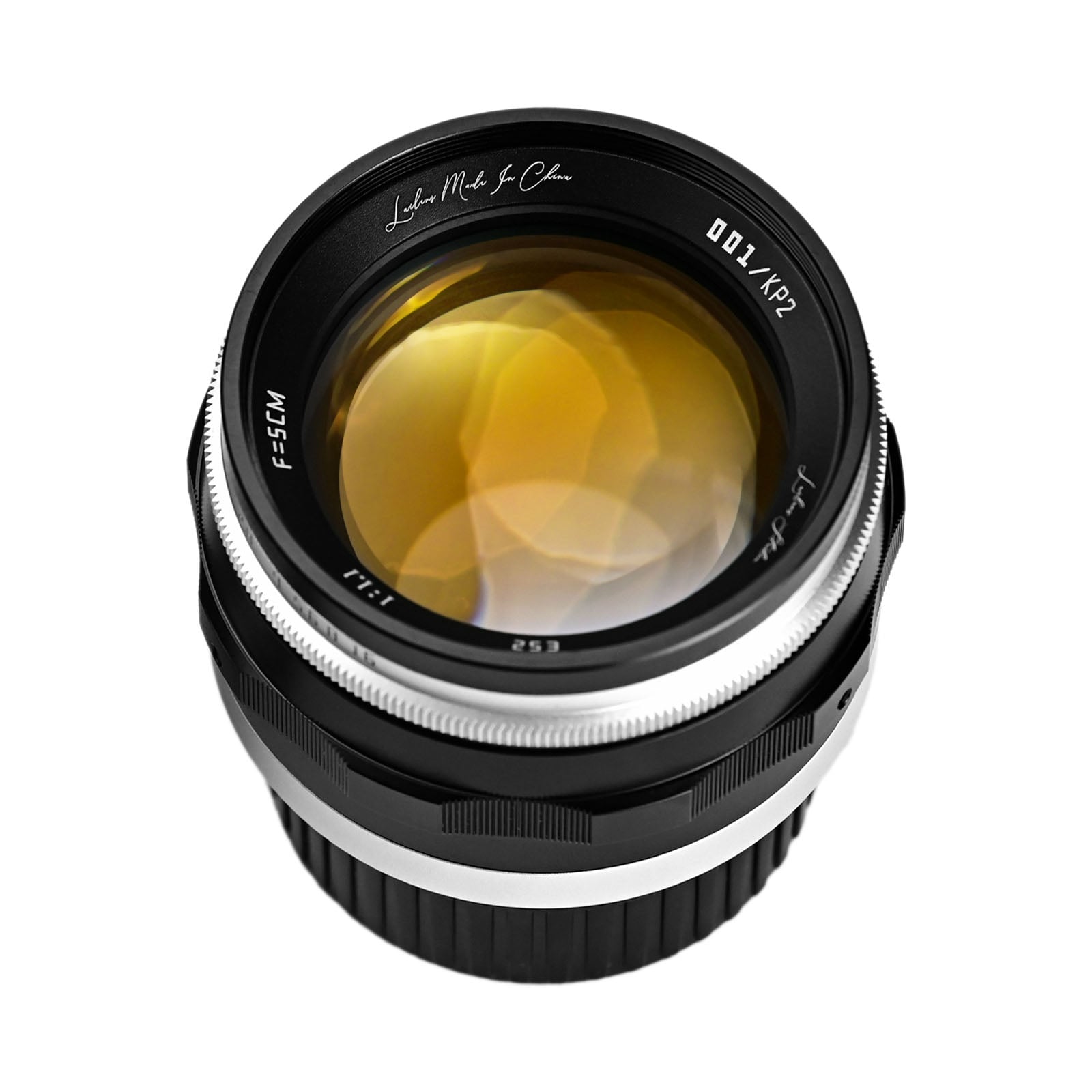 A close-up photo of a camera lens with a black and silver body, displaying yellow reflections on the glass and white markings around the rim.