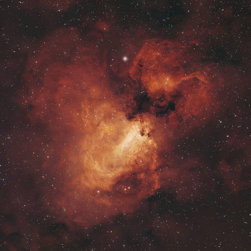 A dense, glowing nebula of orange and red gas clouds filled with numerous bright stars against a dark background.