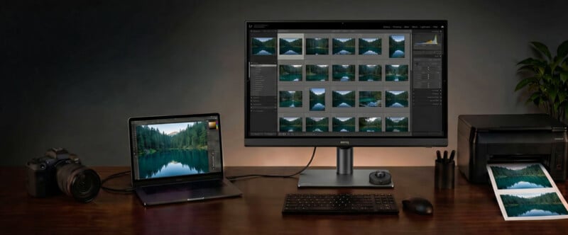 A desk with a camera, laptop, large monitor displaying photo thumbnails, keyboard, mouse, printer, printed photo, and a plant in the background. The workspace is neat and organized for photo editing.