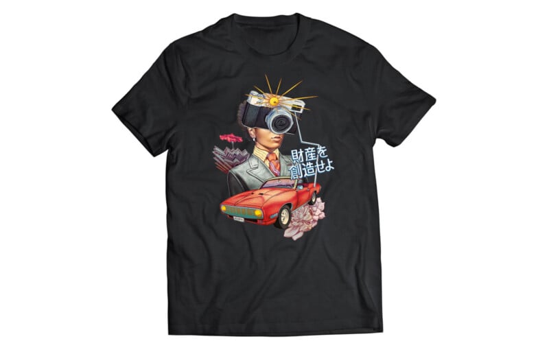 Black T-shirt with a graphic of a woman's head, a camera, a red sports car, pink flowers, and Japanese text. The camera has rays coming out of it. The design is colorful and surreal.