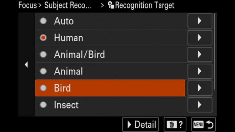 Camera screen showing focus options: Auto, Human, Animal/Bird, Animal, Bird (highlighted in orange), and Insect, with navigation and menu icons at the bottom.