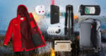 A red jacket, a white travel adapter, a PNY power bank, a tripod, a waterproof phone pouch, three AirTags, a small tan Pelican pouch, and a black rolling suitcase are arranged against a rainy window background.