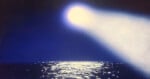 A bright light shines down from the sky onto a dark ocean, creating a glowing reflection on the water's surface under a deep blue night sky.