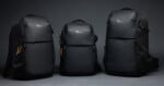 Three black Lowepro backpacks of varying sizes stand side-by-side against a plain gray background.