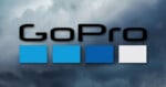 The GoPro logo with four squares in light blue, blue, dark blue, and gray on a cloudy sky background.