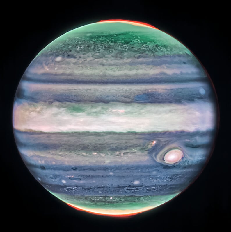 Image of Jupiter with colorful bands, showing green and red hues near the poles, and the Great Red Spot visible on the lower right. The planet appears vibrant against a black background.