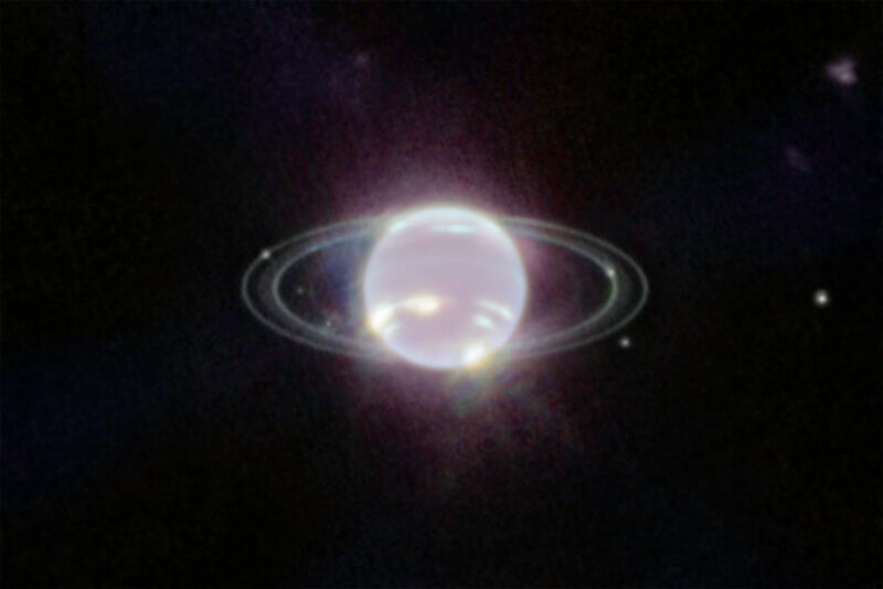 A bright, bluish planet with faint rings and several small moons is seen against a dark space background.