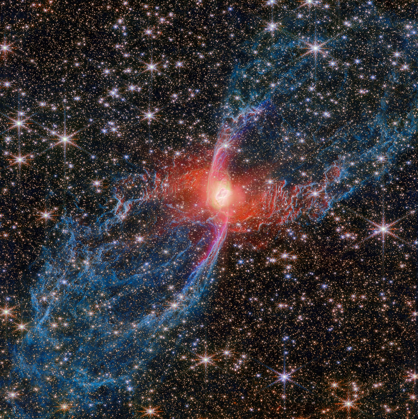 Colorful nebula with a bright red center, surrounded by blue and pink wispy clouds and many sparkling stars scattered throughout the dark space background.