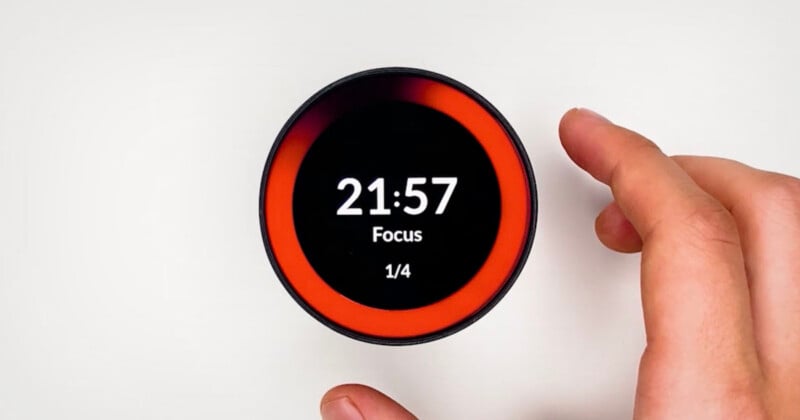 A hand adjusts a round digital timer displaying 