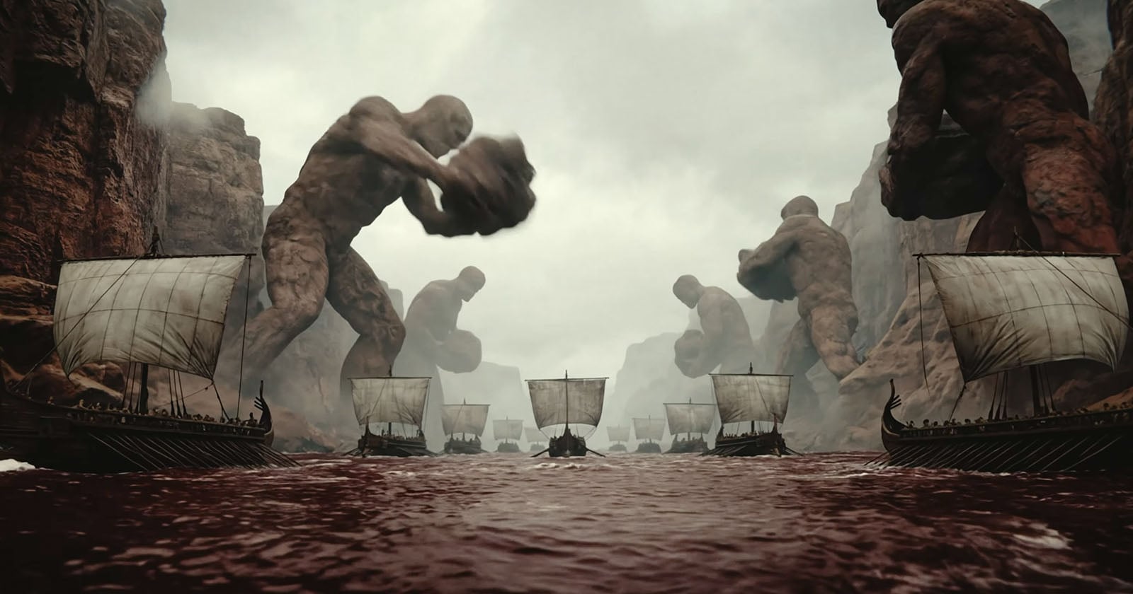 Several large stone giants stand in a canyon, holding boulders over Viking-style ships sailing on a red river under a cloudy sky.