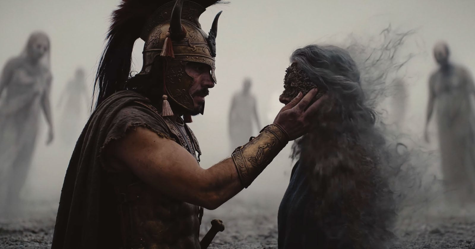 A warrior in ancient armor touches the face of a decaying, ghostly figure as shadowy phantoms loom in the foggy background.