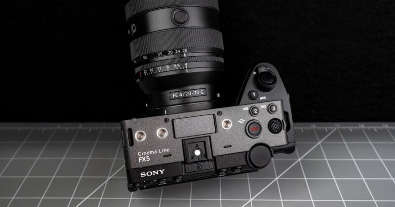 A Sony Cinema Line FX5 camera with an attached FE 4/20-70 G lens is positioned on a gray grid-pattern surface, viewed from above with controls and buttons visible.