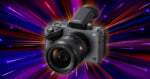 A Sony Alpha camera with a lens is centered against a vibrant, colorful background of radiating light streaks in blue, pink, orange, and purple.