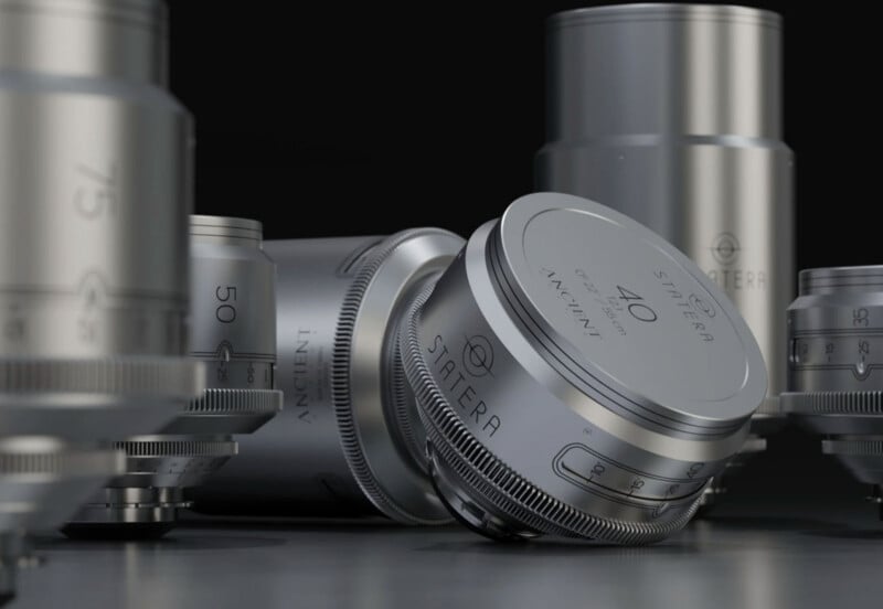 Close-up of several metallic camera lenses arranged on a dark surface, with one labeled “SATERRA 40 ANCIENT” prominently displayed in the center, surrounded by other lenses with engraved focal lengths.