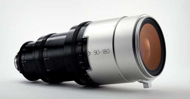 A professional camera lens with a metallic silver finish and black focus rings, marked 
