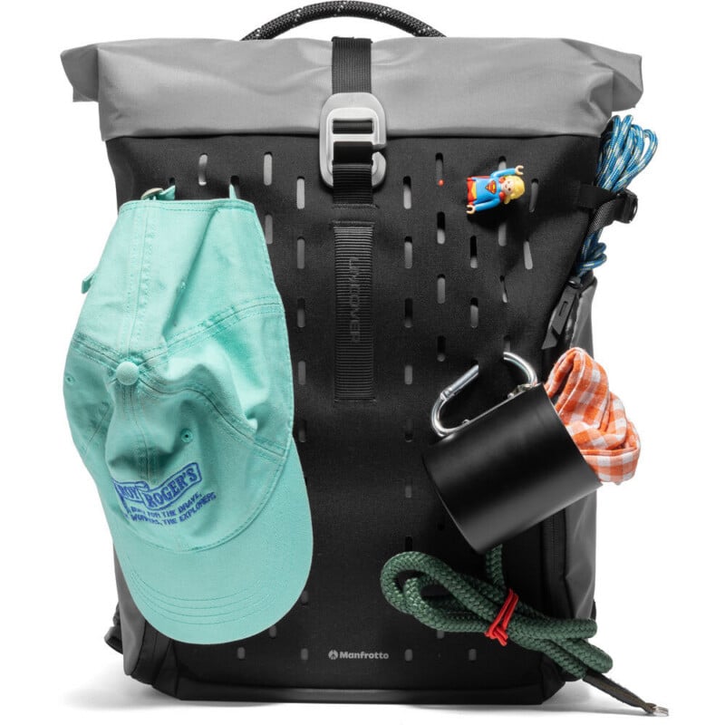 A black and gray backpack with a turquoise cap, orange checkered cloth, black mug, green rope, blue rope, and a small cartoon keychain attached to the front.