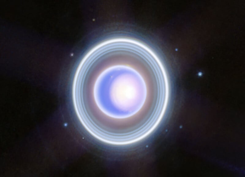 A bright, glowing sphere with blue and white rings surrounds it, set against a dark space background with small scattered stars.