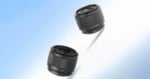 Two black camera lenses are displayed against a gradient blue and white background, with one lens casting a faint shadow beneath it.
