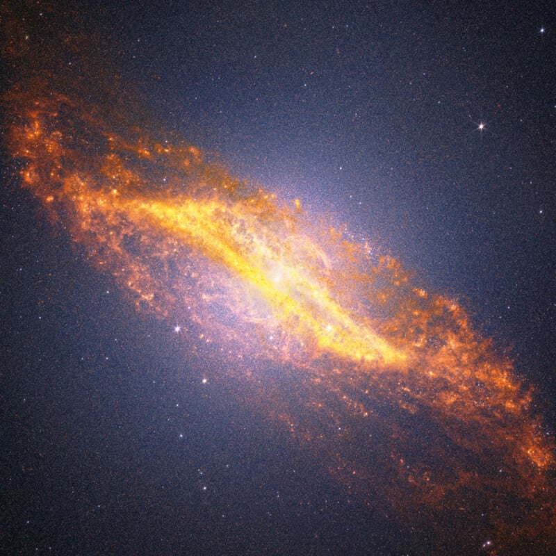 A bright, colorful spiral galaxy glows with vivid yellow, orange, and red clouds of gas and dust, surrounded by countless white stars against the dark background of space.