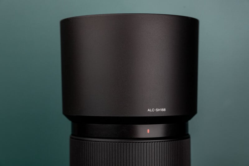 A black camera lens hood with the text "ALC-SH188" printed on it, positioned above a lens barrel with a small red alignment dot.