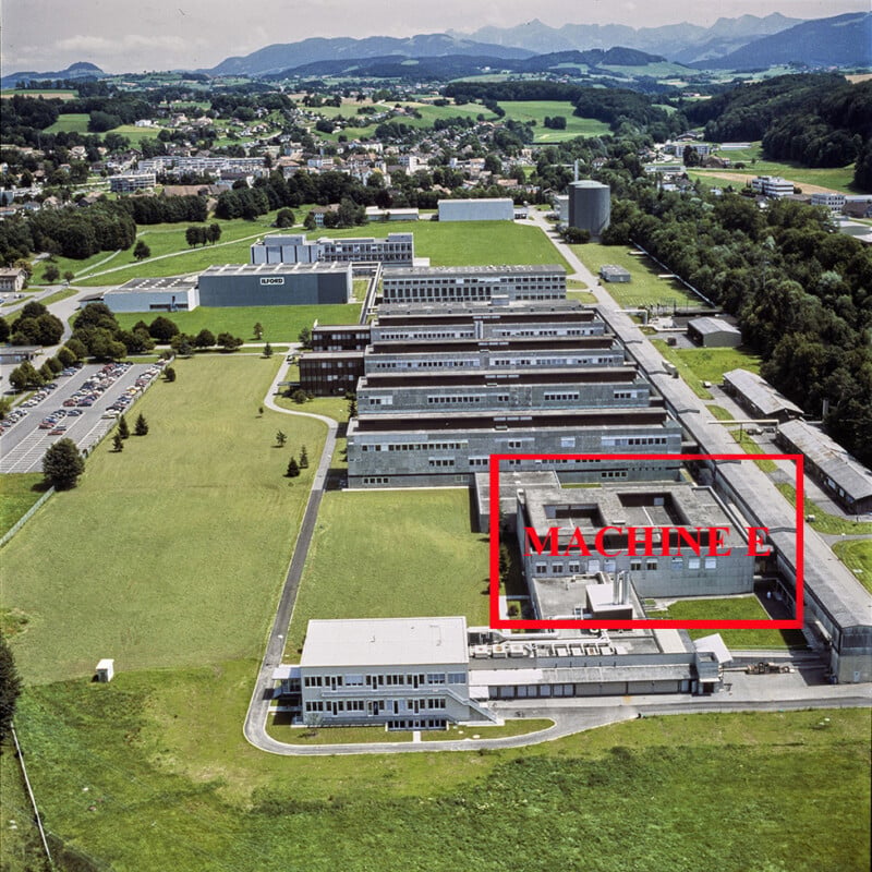 An aerial view of a large industrial complex with a red box labeled "MACHINE E" highlighting a specific building section.