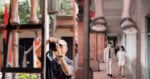 A split-screen view shows a photographer on the left taking a picture of a couple walking together in a corridor on the right.