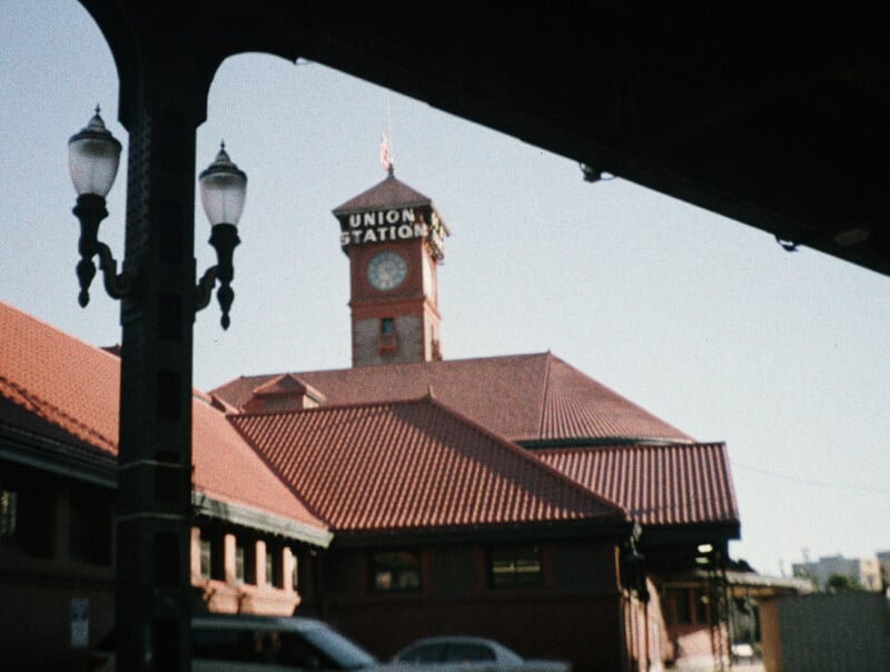 A view of a brick Union Station building with a clock tower, framed by a dark architectural overhang and a street lamp in the foreground.
