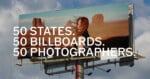 A large outdoor billboard against a cloudy sky features a woman with windblown hair standing in front of a desert landscape, with the text 