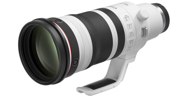 A white telephoto camera lens with a black zoom ring, a tripod mount, and several control switches on the side.