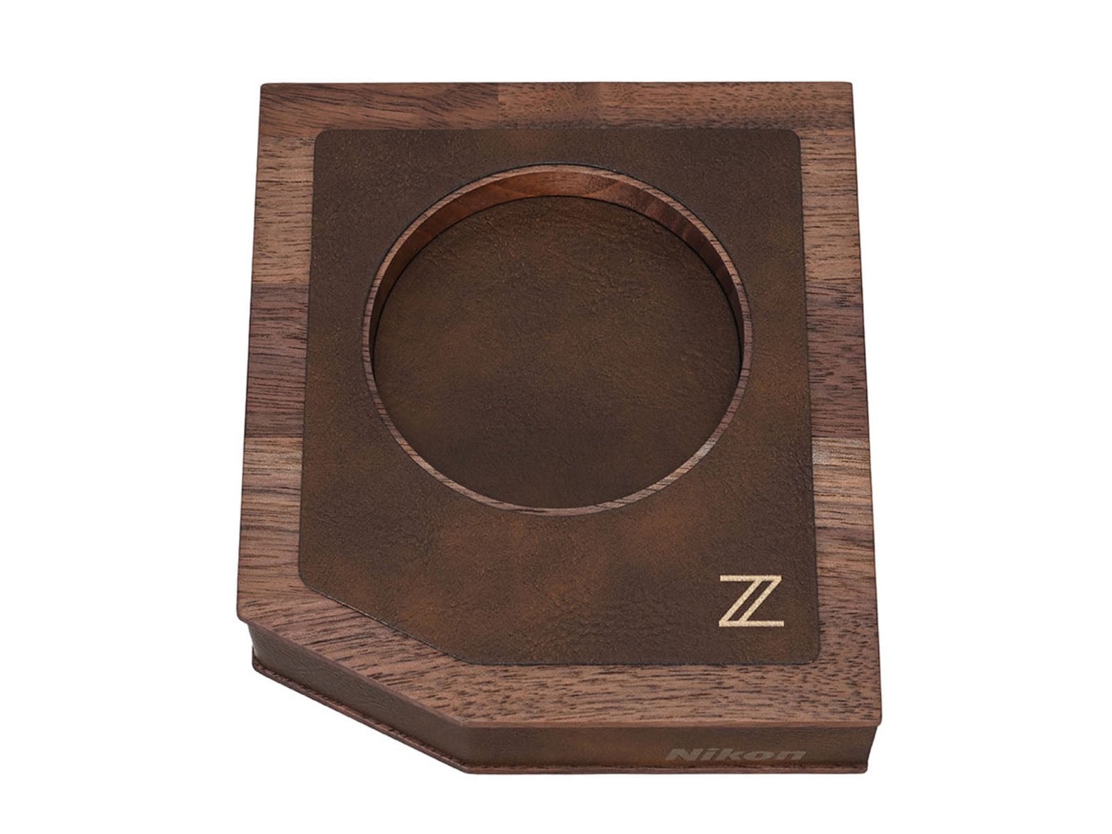 A wooden display stand with a circular cutout, a brown textured inlay featuring a gold "Z" logo, and the word "Nikon" printed on the front edge.