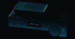 A dark, rectangular electronic device with a small screen displaying the text "G X - P 1" and a circular dial on the right side.