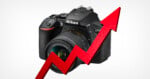 A Nikon D5600 camera is positioned behind a large, red, zigzagging upward-pointing arrow against a plain white background.