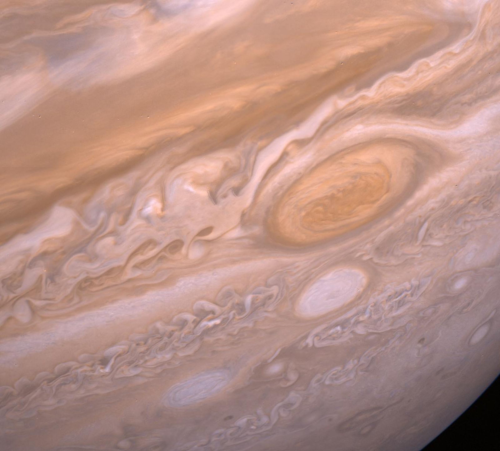 A close-up view of Jupiter's swirling, tan-colored cloud bands featuring the large, oval-shaped Great Red Spot.