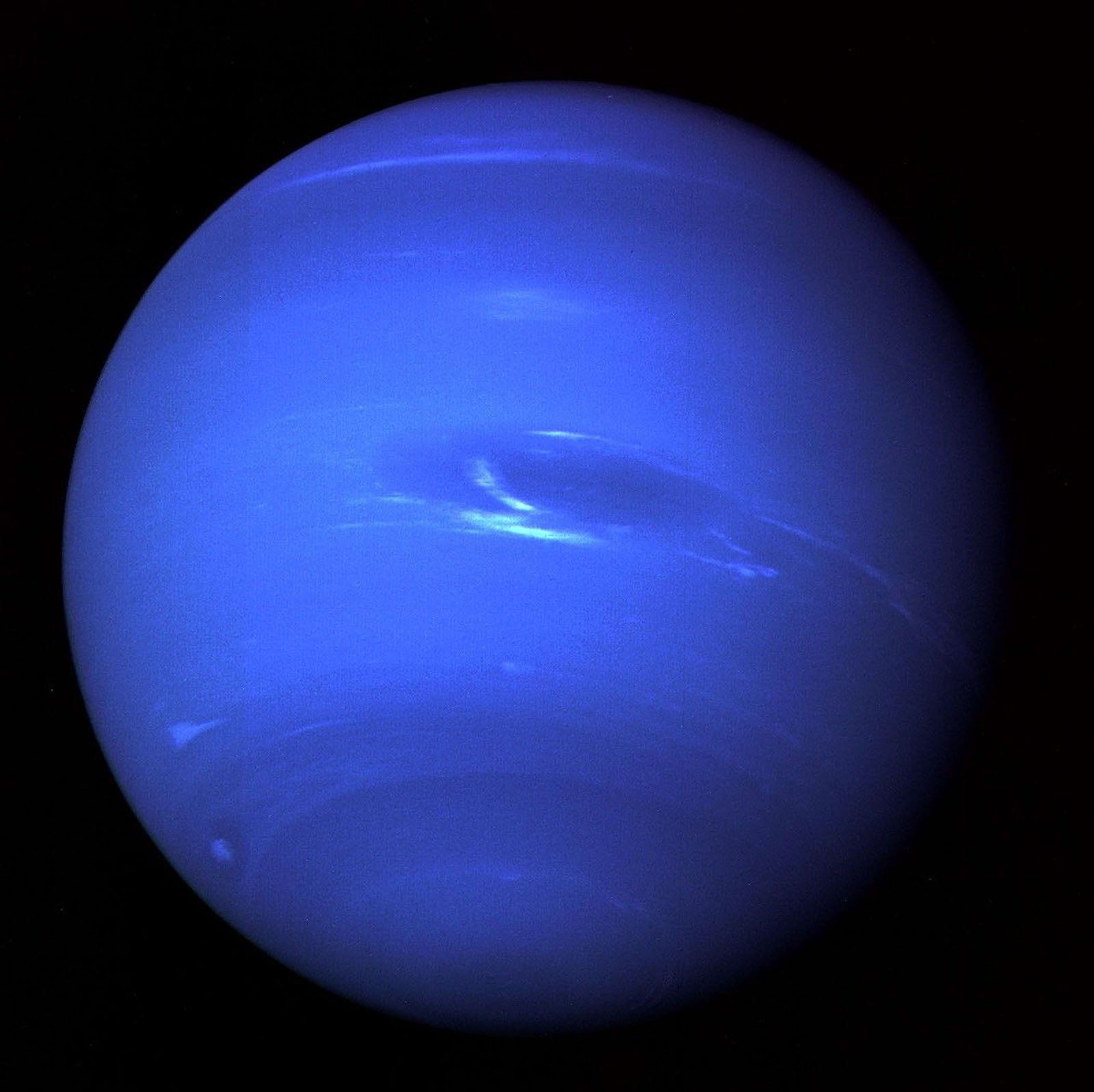 The planet Neptune appears as a vibrant blue sphere set against a black background, featuring faint, wispy white cloud bands.