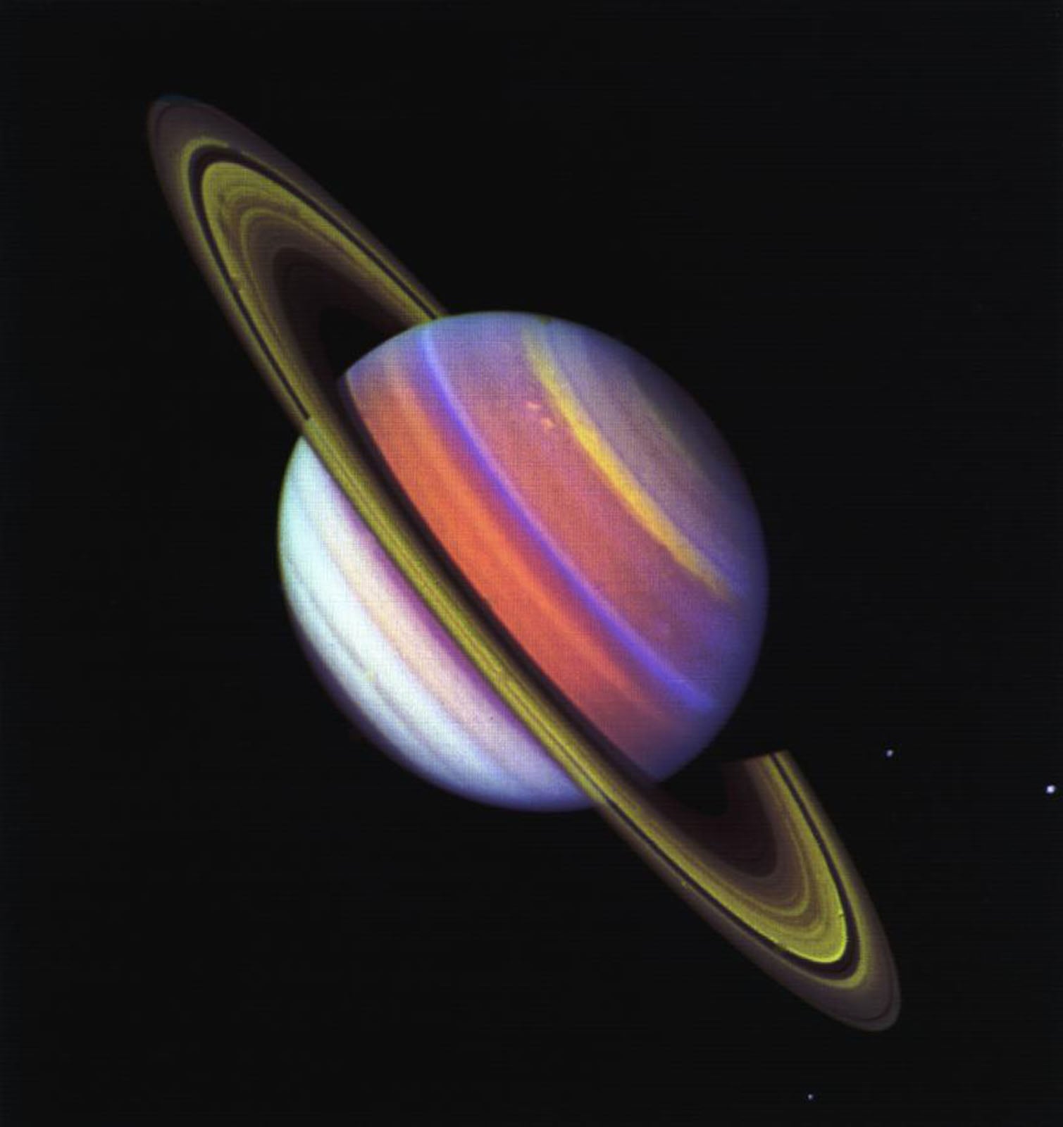 A vibrant, false-color view of the planet Saturn and its rings set against a black background.