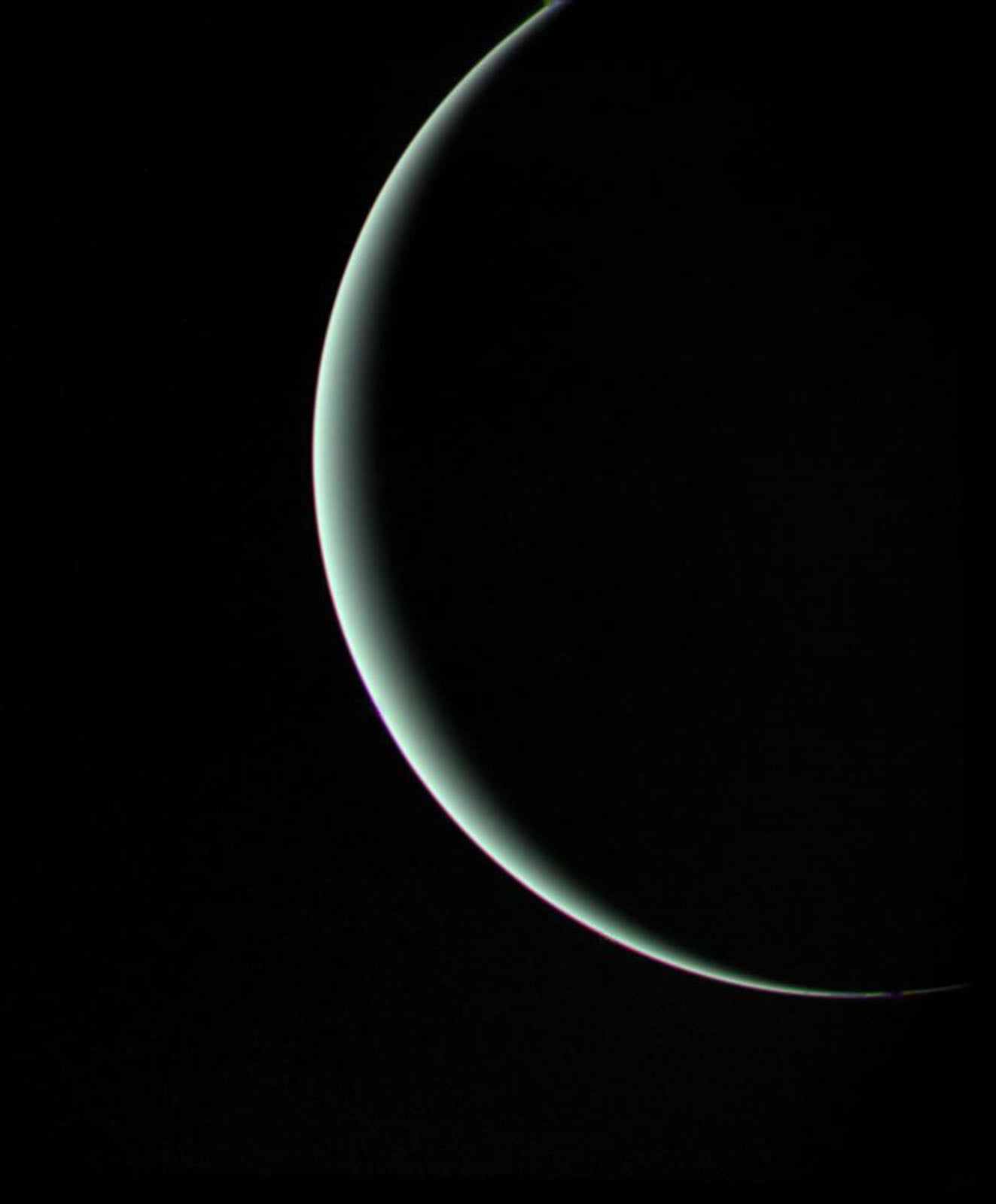 A thin, glowing crescent of a planet or moon is visible against a deep black background.