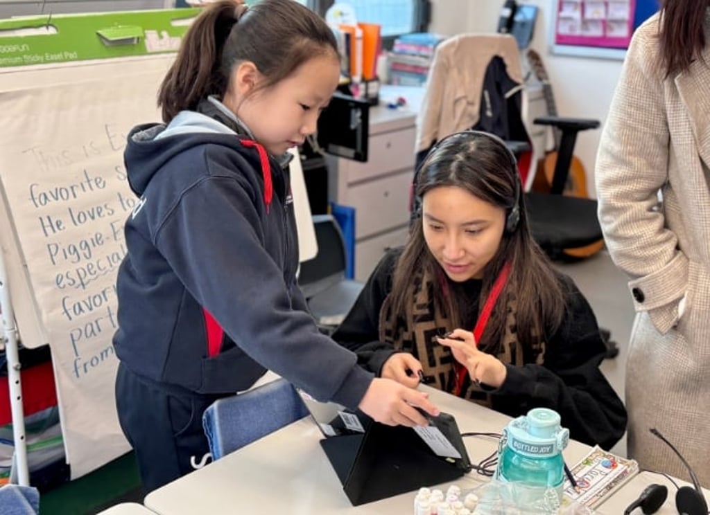 Grade 3 students present their work using tablets, allowing them to develop public speaking skills from a young age. This practice enhances their confidence and communication skills.