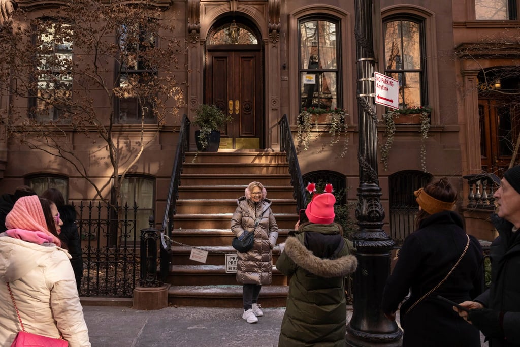 A person poses for a photo in front of the Manhattan brownstone where Carrie Bradshaw lived in Sex and the City. The city’s Landmarks Preservation Commission approved an application to put a metal gate on the front staircase to keep away tourists. Photo: AP