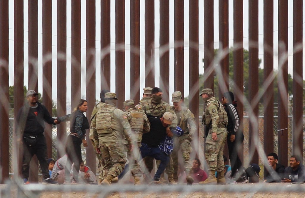 Texas National Guard struggle with a migrant after he crossed across the Rio Grande river to reach the US side. File photo: TNS