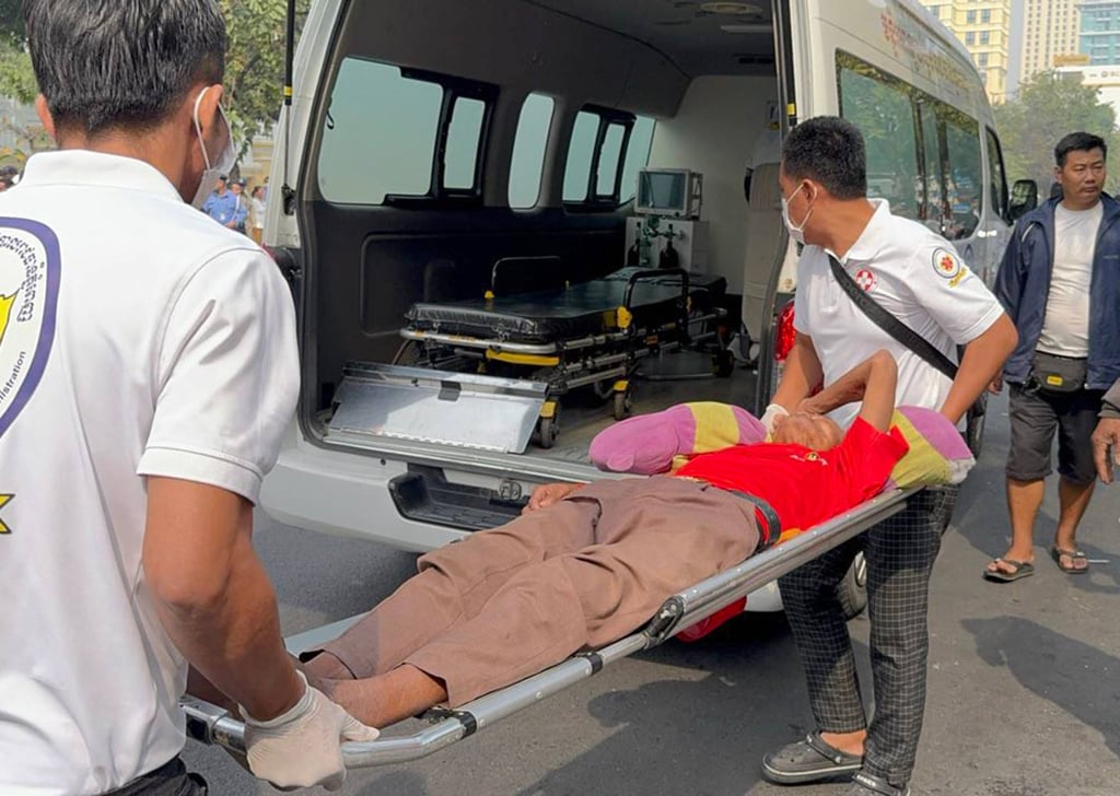 Health workers carry a person into an ambulance after a crowd pushed towards the mansion gates of Cambodian tycoon Sok Kong to receive red envelopes filled with money. Photo: AFP/Fresh News