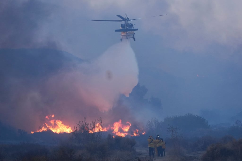 A helicopter drops water on the Hughes Fire. Photo: AP